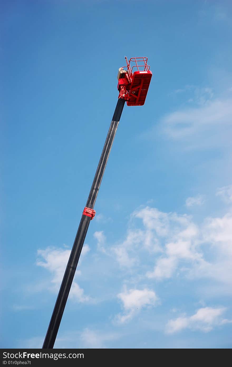 Red hydraulic cherry picker over blue sky