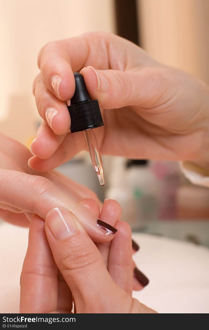 Moisteriser being applied to a womans finger nail. Moisteriser being applied to a womans finger nail.