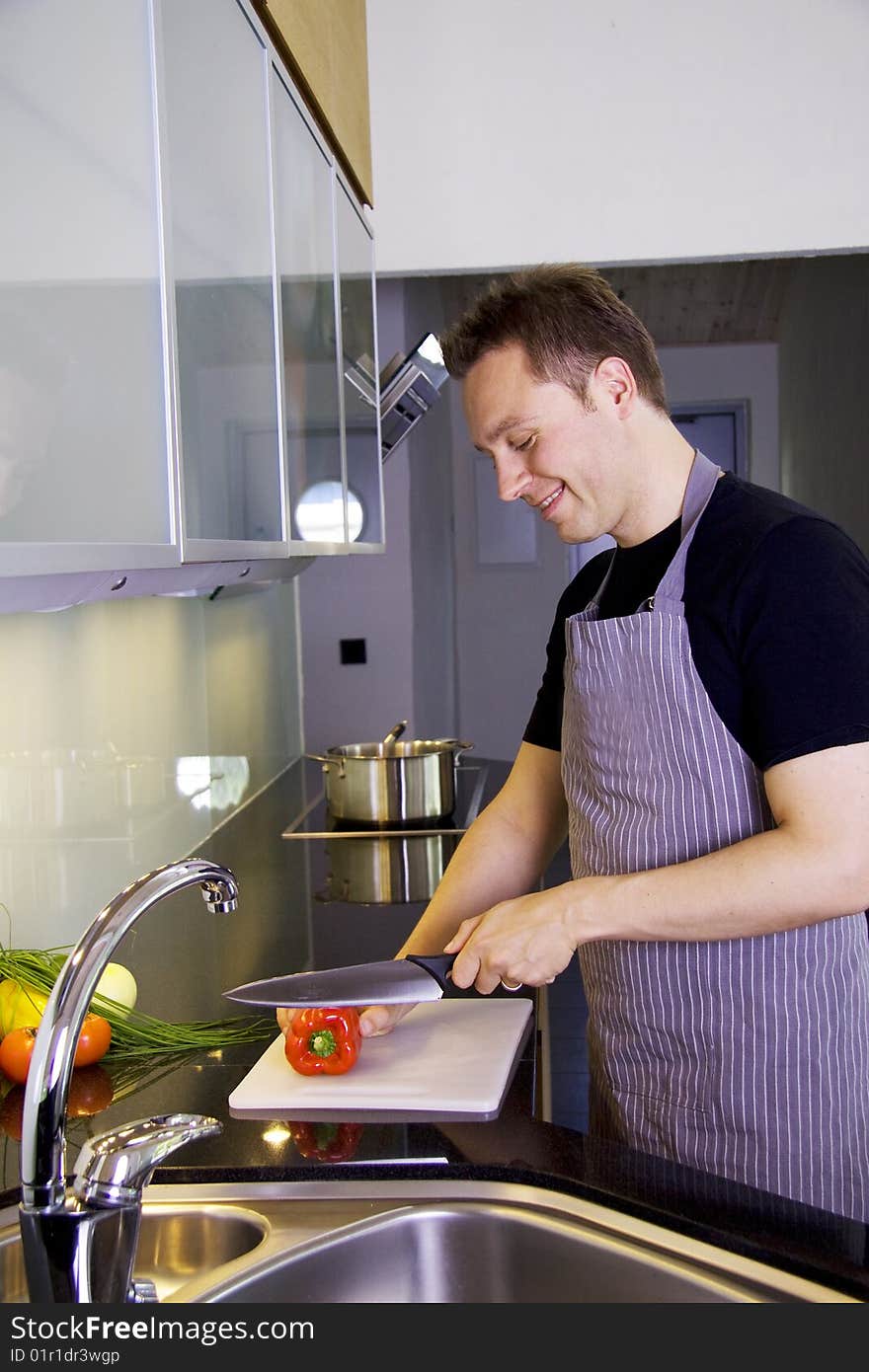 A man is cooking in a modern kitchen. He is chopping vegetables. A man is cooking in a modern kitchen. He is chopping vegetables