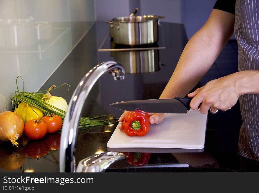 A man is cooking in a modern kitchen. He is chopping vegetables. A man is cooking in a modern kitchen. He is chopping vegetables