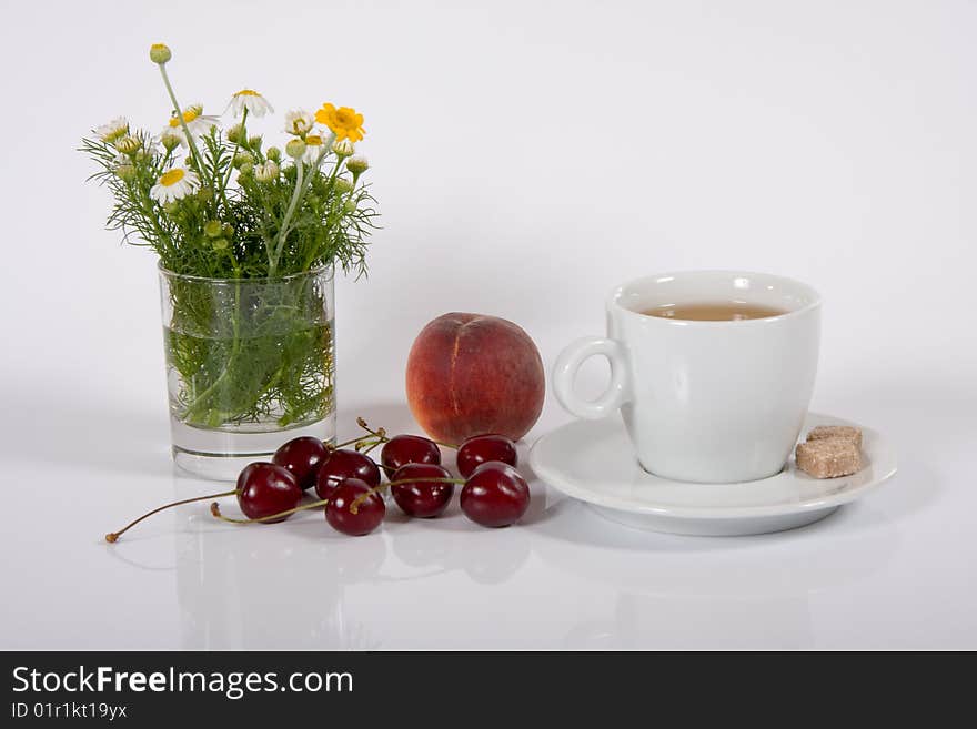 Cup of tea with fruits and horse gowan on white. Cup of tea with fruits and horse gowan on white