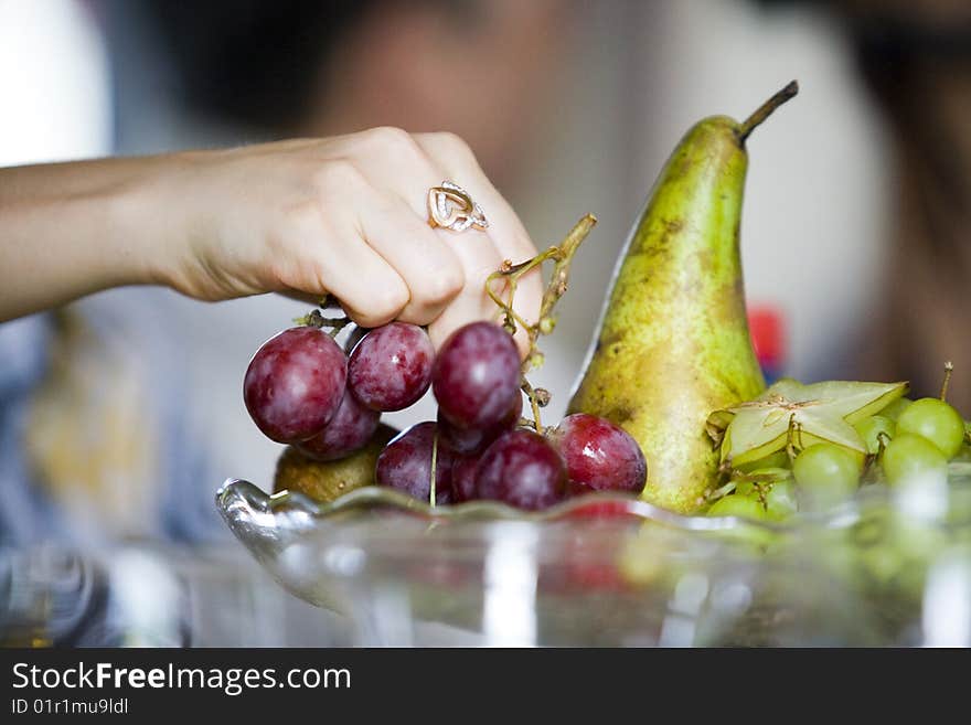 Woman takes fruits from vase.