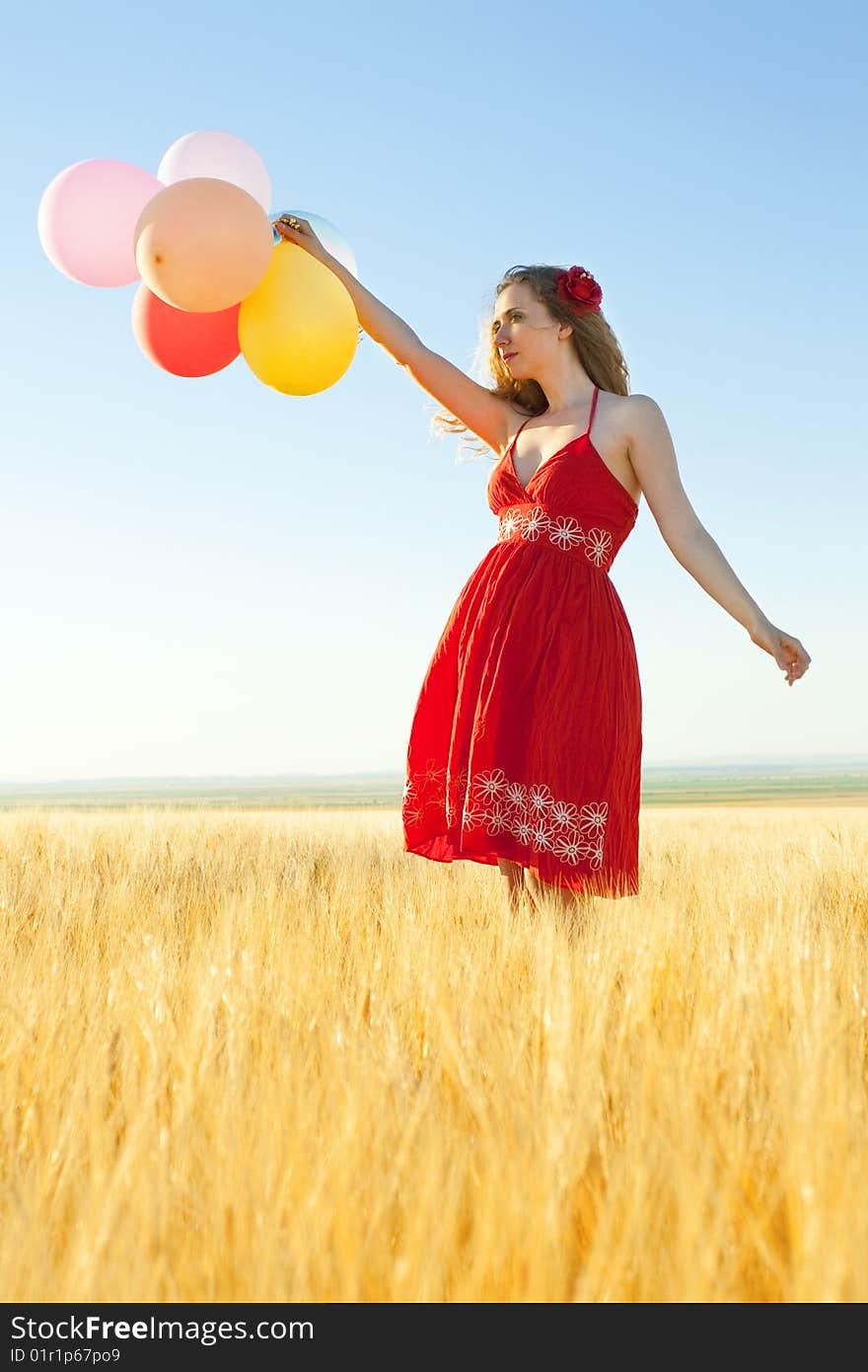 Young woman in a wheat field holding colorful balloons. Young woman in a wheat field holding colorful balloons