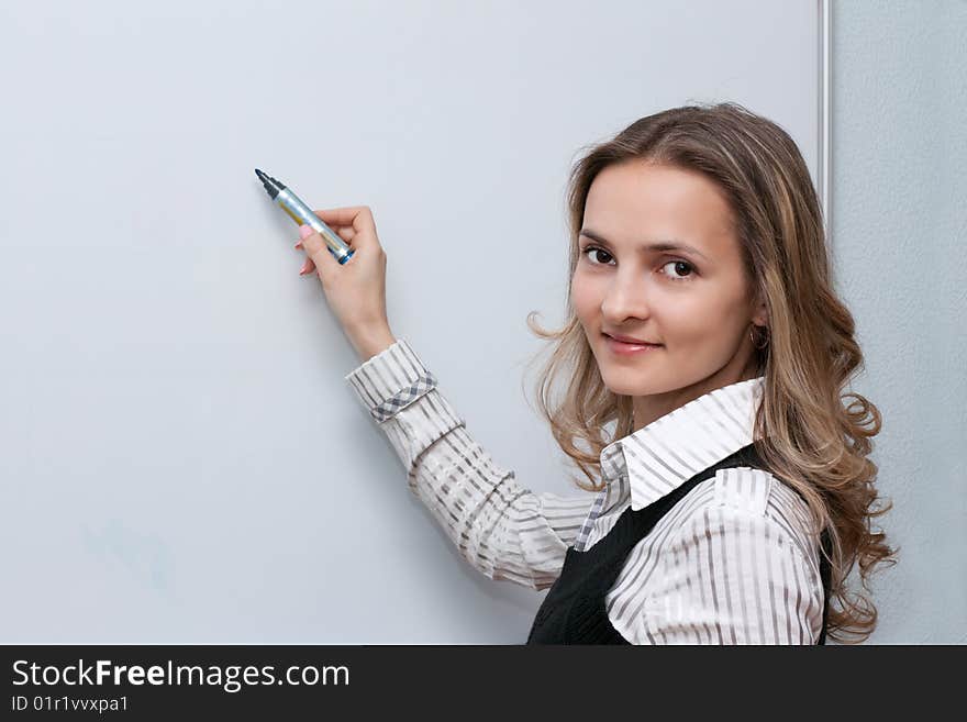 Beautiful girl with long hair shows marker on white sheet of paper