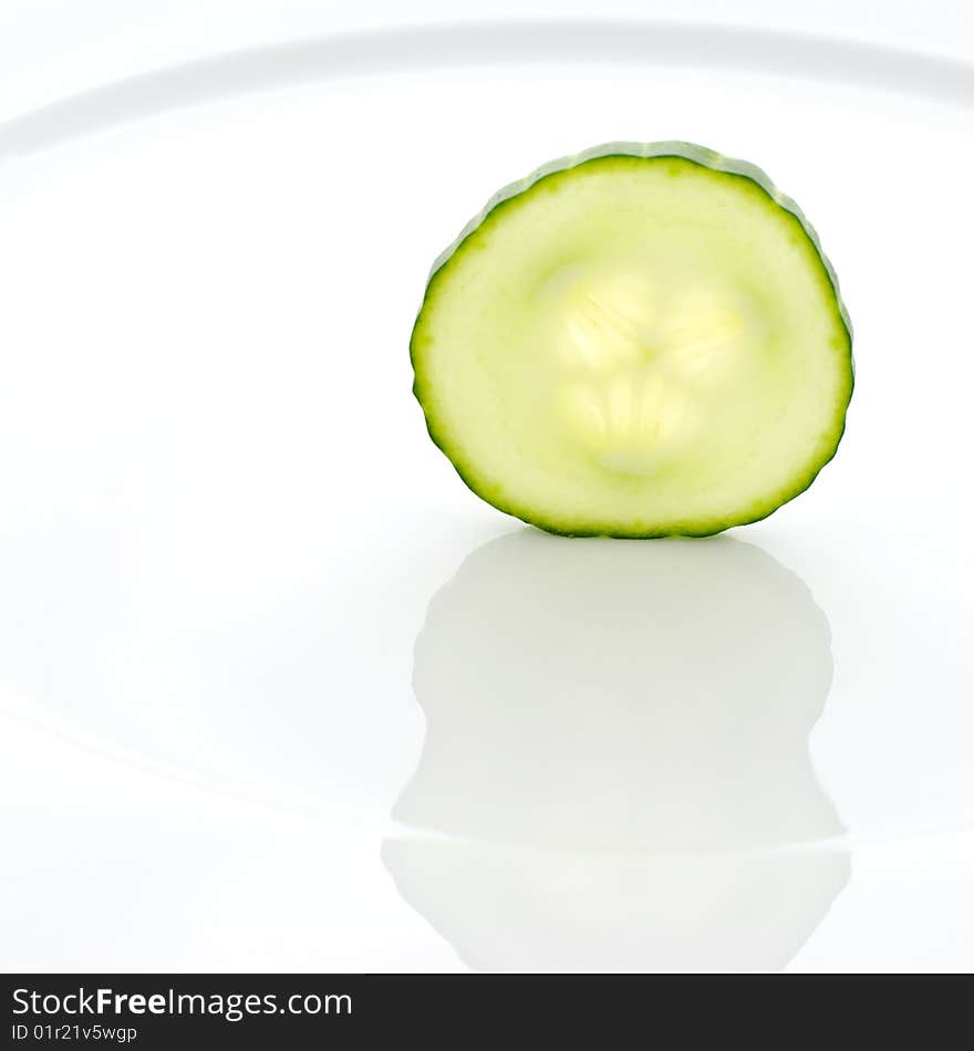 Slice of a cucumber standing on a white plate. Slice of a cucumber standing on a white plate.