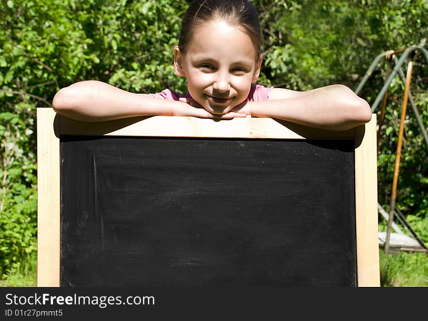 Young girl leaning on a blackboard