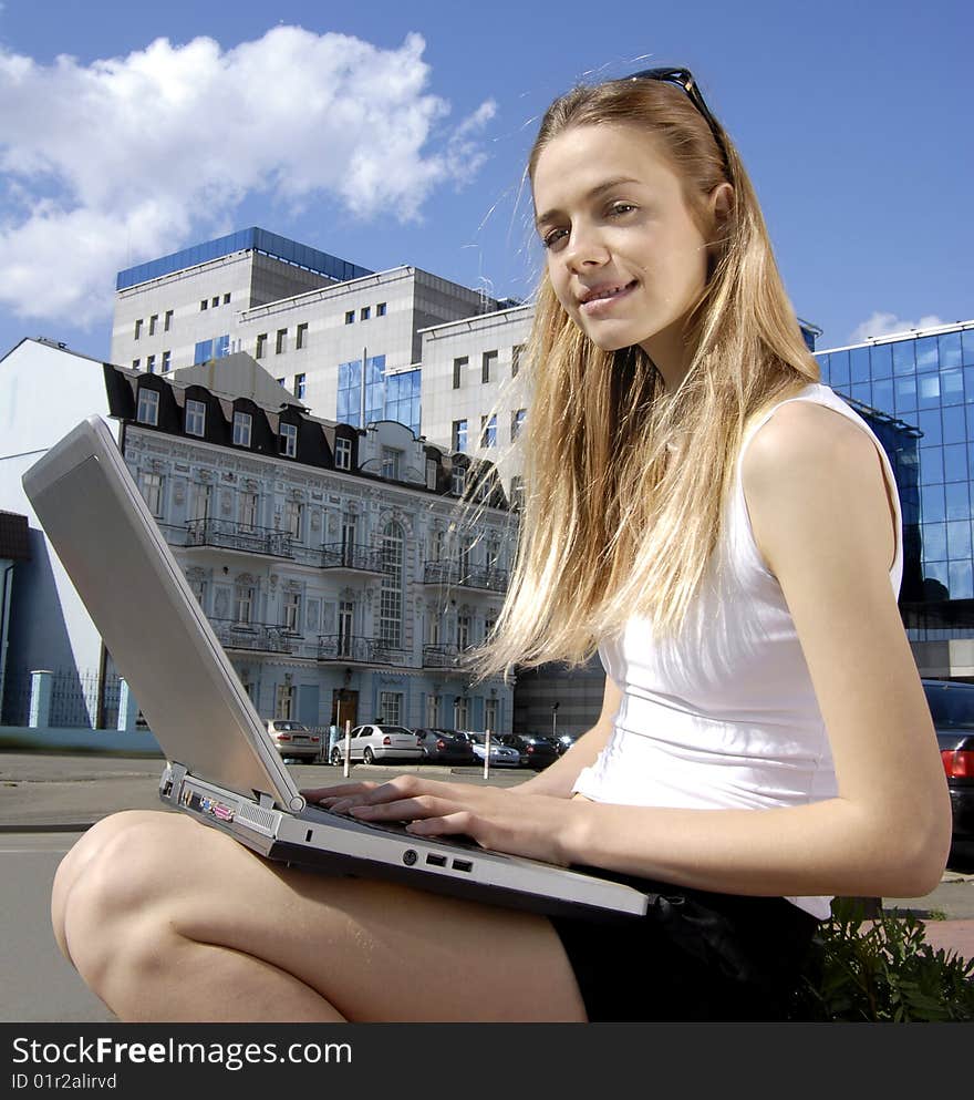 Happy collegian with laptop computer near a modern building. Happy collegian with laptop computer near a modern building