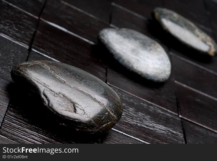 3 river rocks on black wood