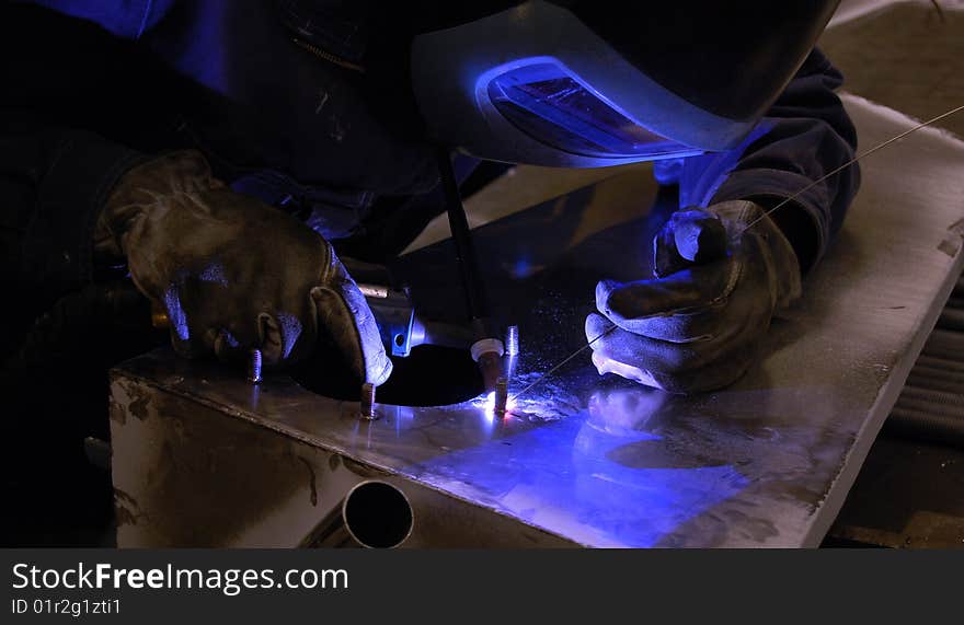 A person welding using TIG on a stainless steel tank. A person welding using TIG on a stainless steel tank