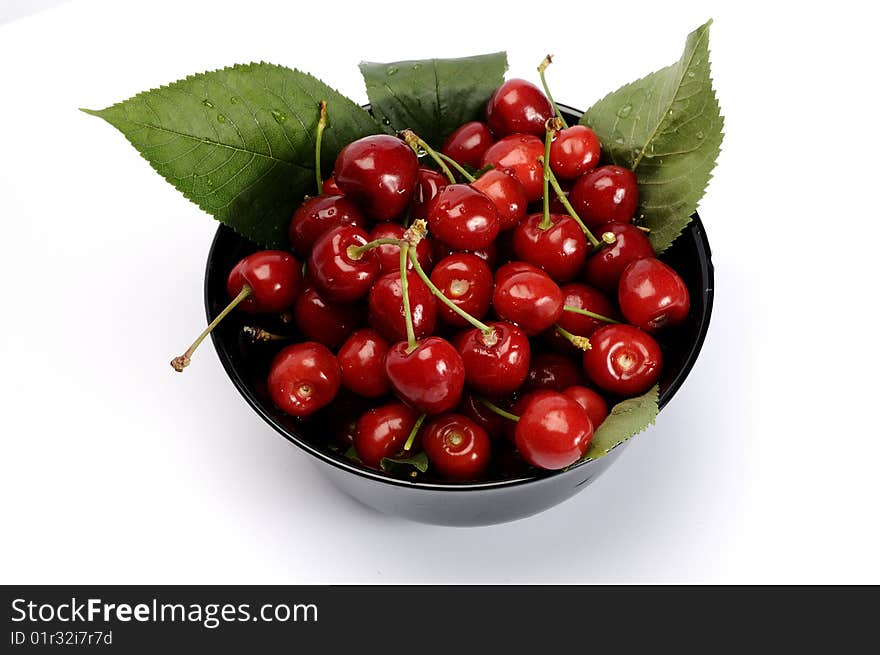 Black bowl with cherries isolated on white. Black bowl with cherries isolated on white