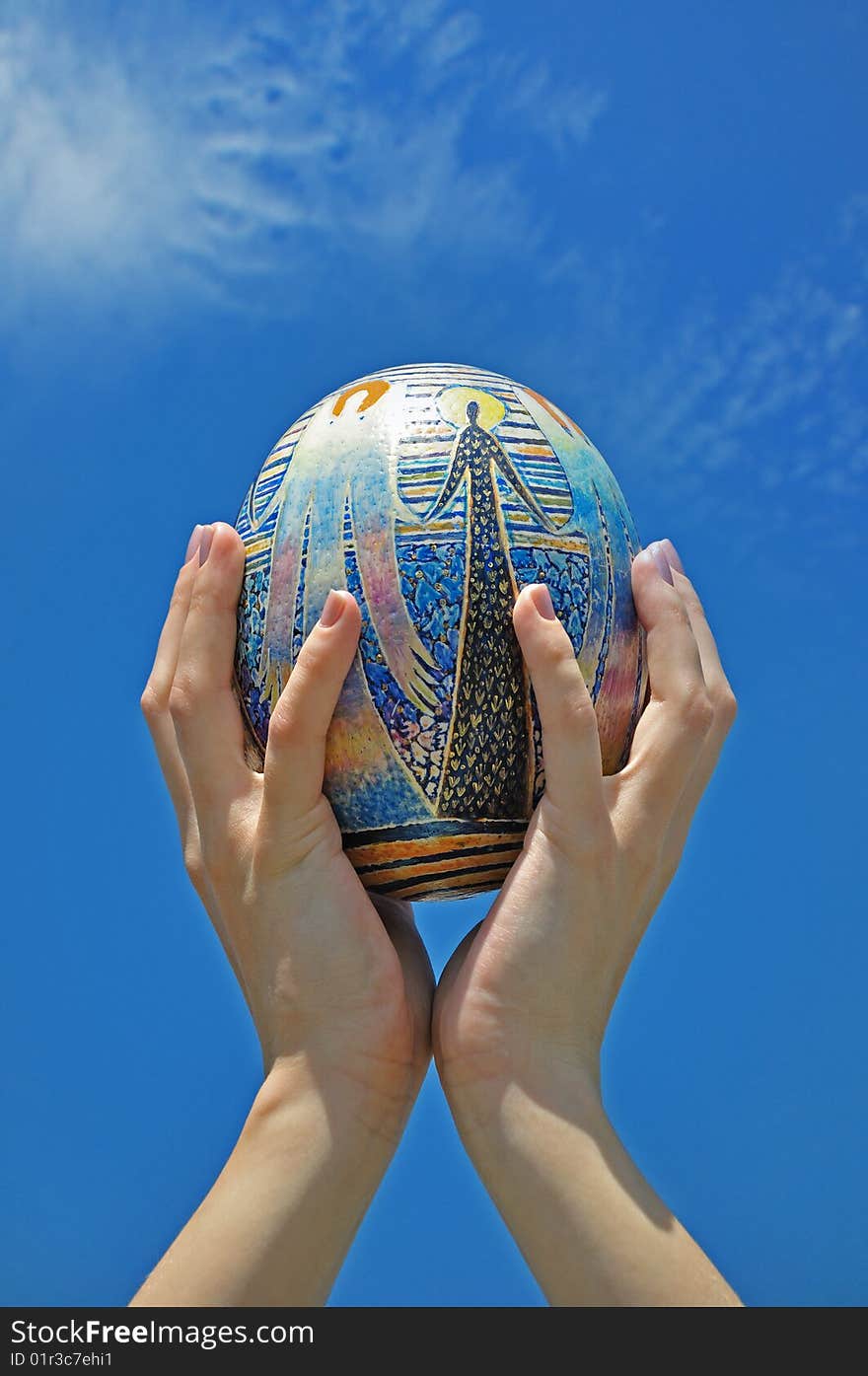 Easter egg in hands against the sky