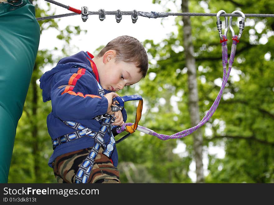 Summer time. Young boy climbing in the forest.