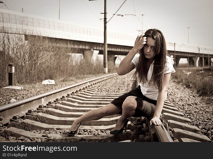 The girl sits on rails near to a motorway. The girl sits on rails near to a motorway