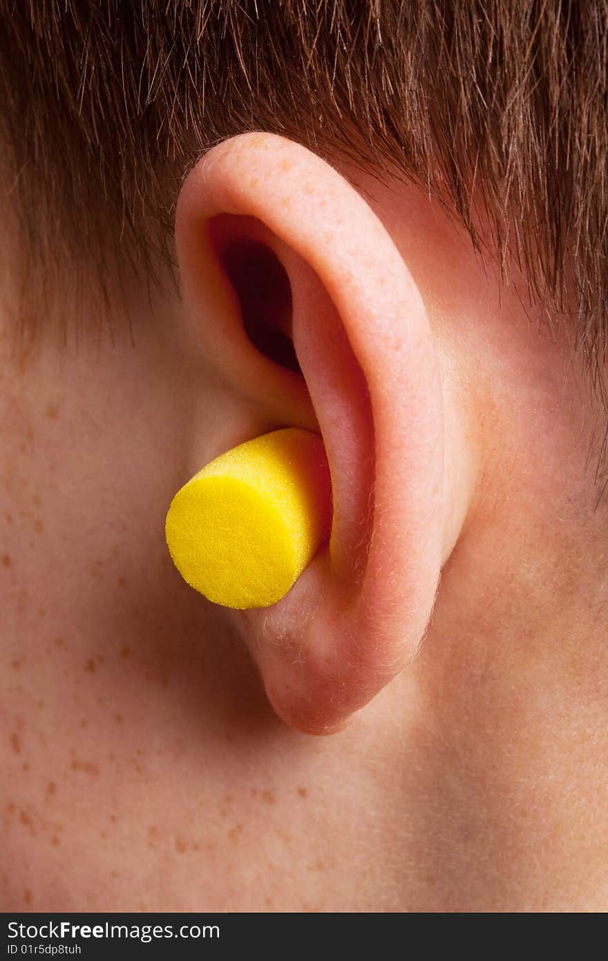 Yellow earplug into the ear close up