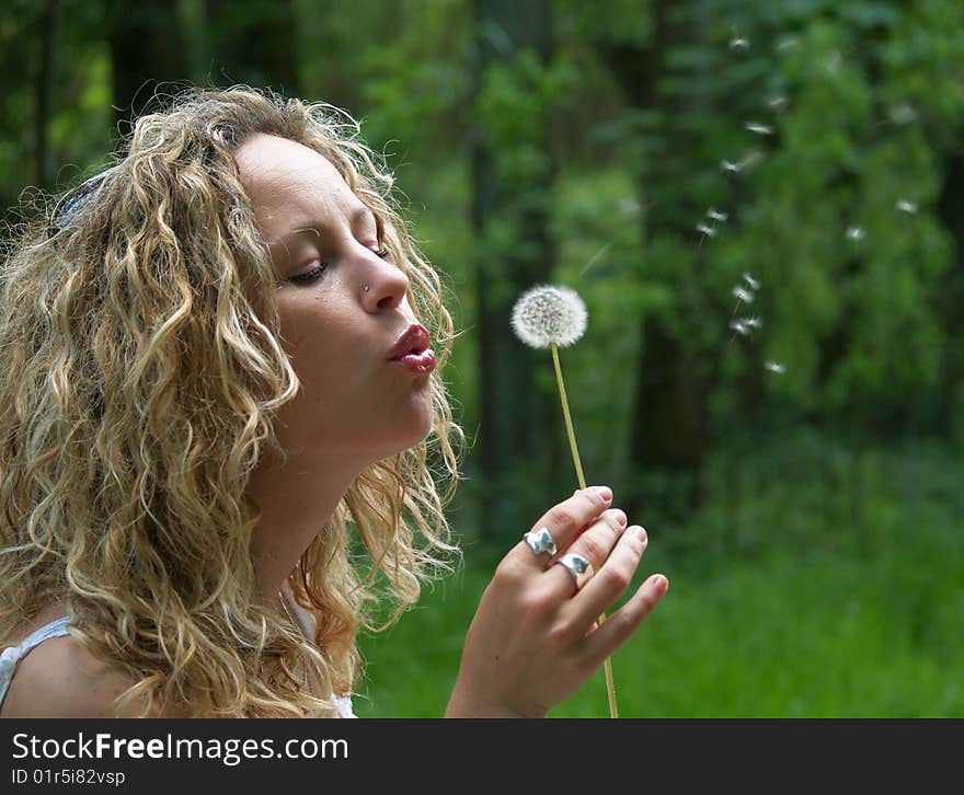 Curly girl blows dandelion