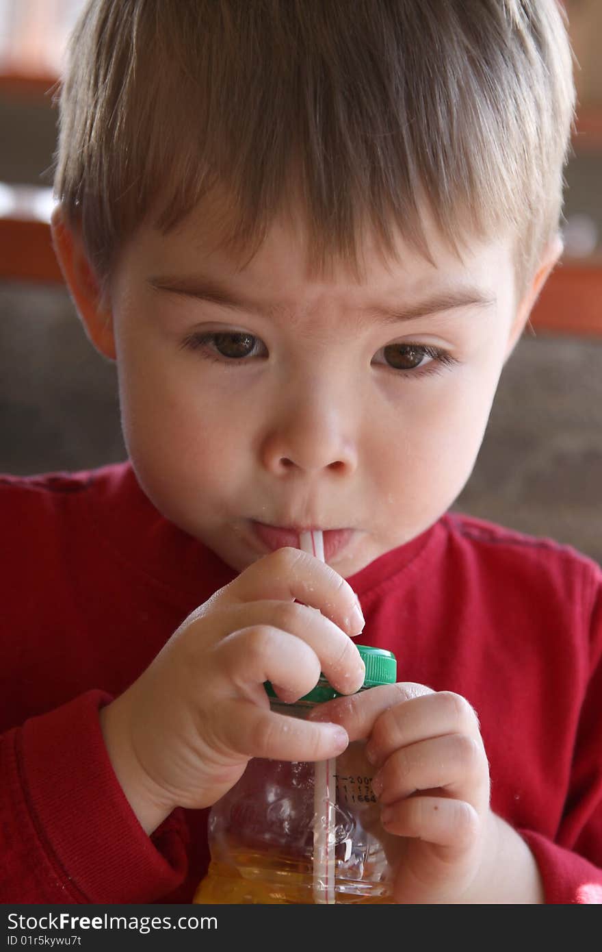 A young boy drinking juice through a straw.