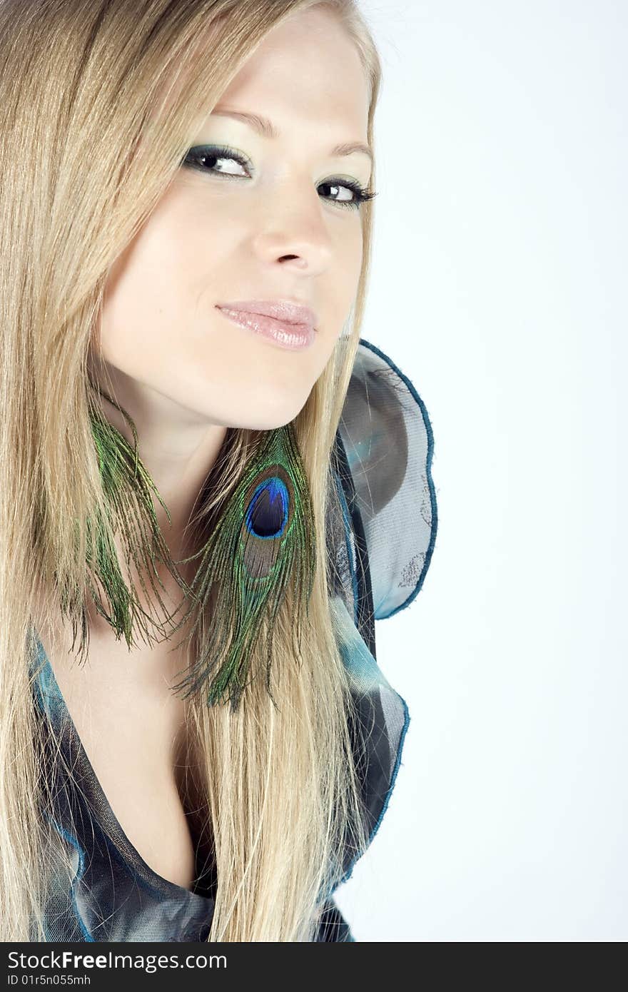 Beautiful young blond model with peacock earrings posing in studio shot. Beautiful young blond model with peacock earrings posing in studio shot