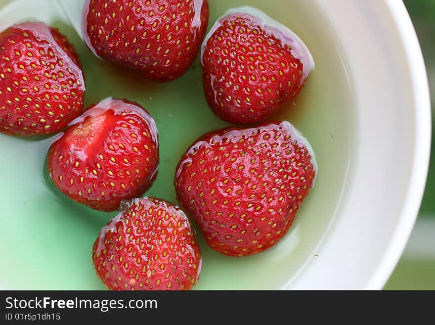 Red strawberries in green jelly, served in white bowl