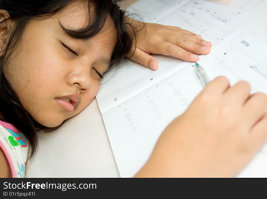 Asian elementary school girl fall a sleep on the table while doing math homework, seems exhausted. Asian elementary school girl fall a sleep on the table while doing math homework, seems exhausted.