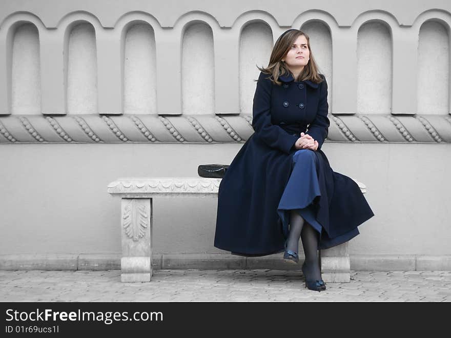 Woman in blue coat sitting on stone bench. Woman in blue coat sitting on stone bench