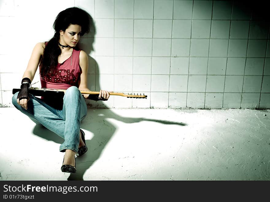 Punk Girl playing guitar on an underground background high contrast. Punk Girl playing guitar on an underground background high contrast