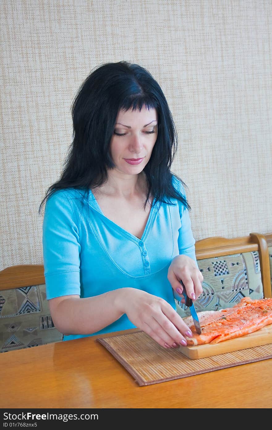 Girl in the kitchen carve fish trout. Girl in the kitchen carve fish trout