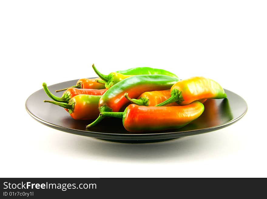 Red and green chillis on a black plate with clipping path on a white background