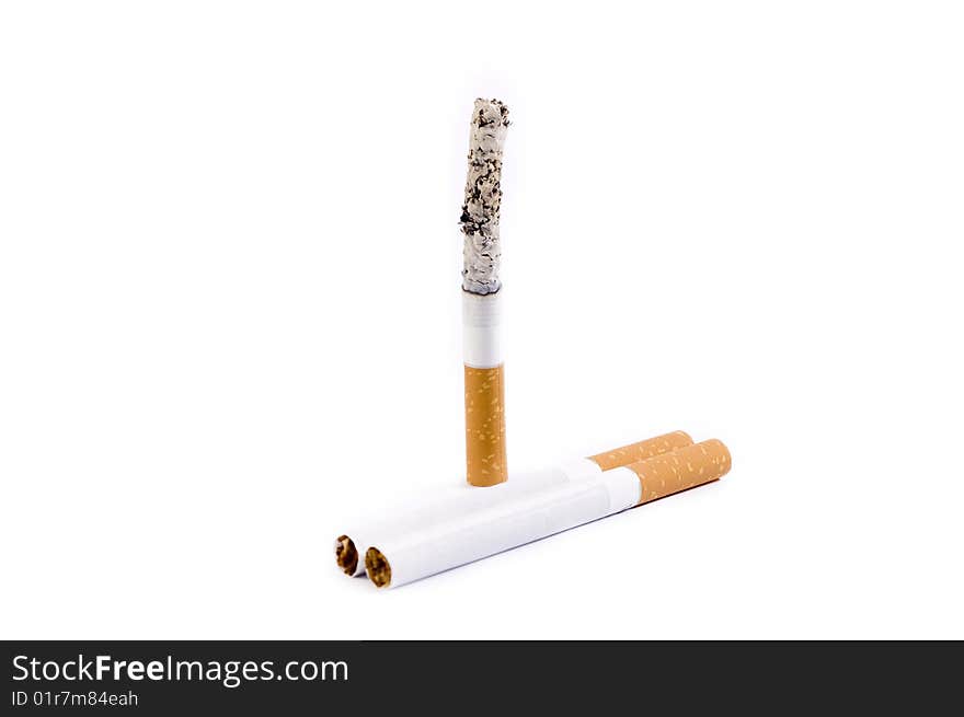 Vertically standing burning cigarette with two cigarettes near. Vertically standing burning cigarette with two cigarettes near