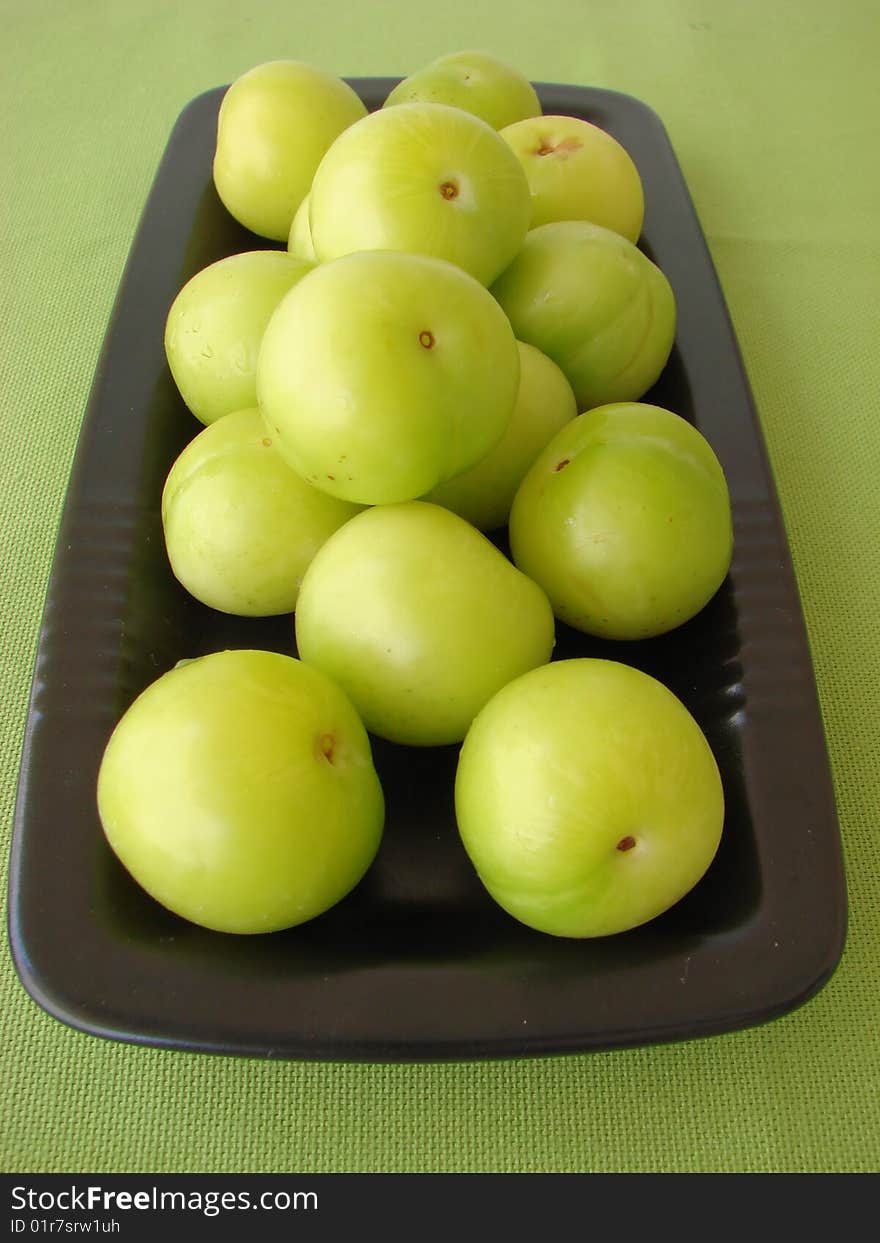 Green plums on a black plate