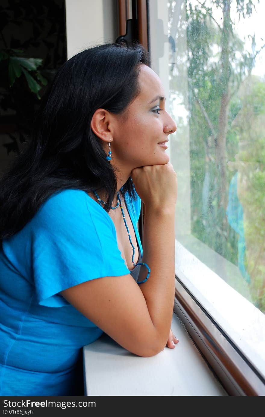 Beautiful Hispanic young woman looking out of a window