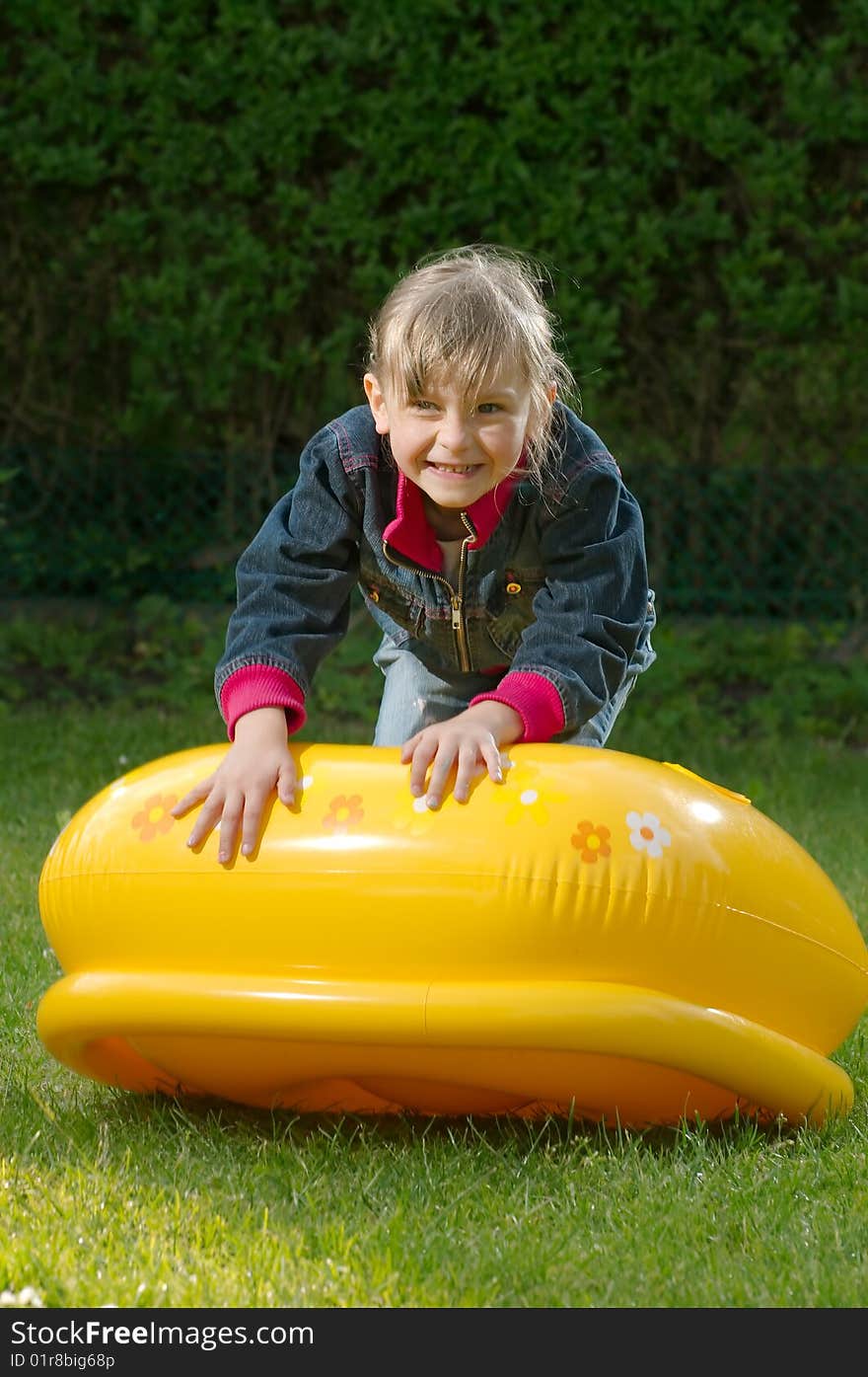 Young girl is climbing on the blowed toy