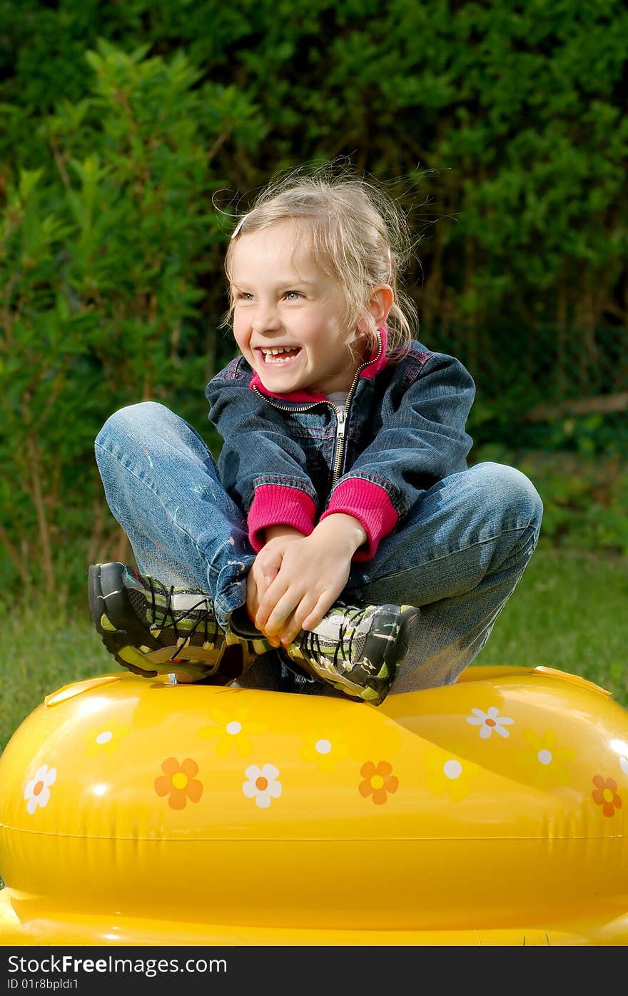 Young girl is sitting on the blown toy