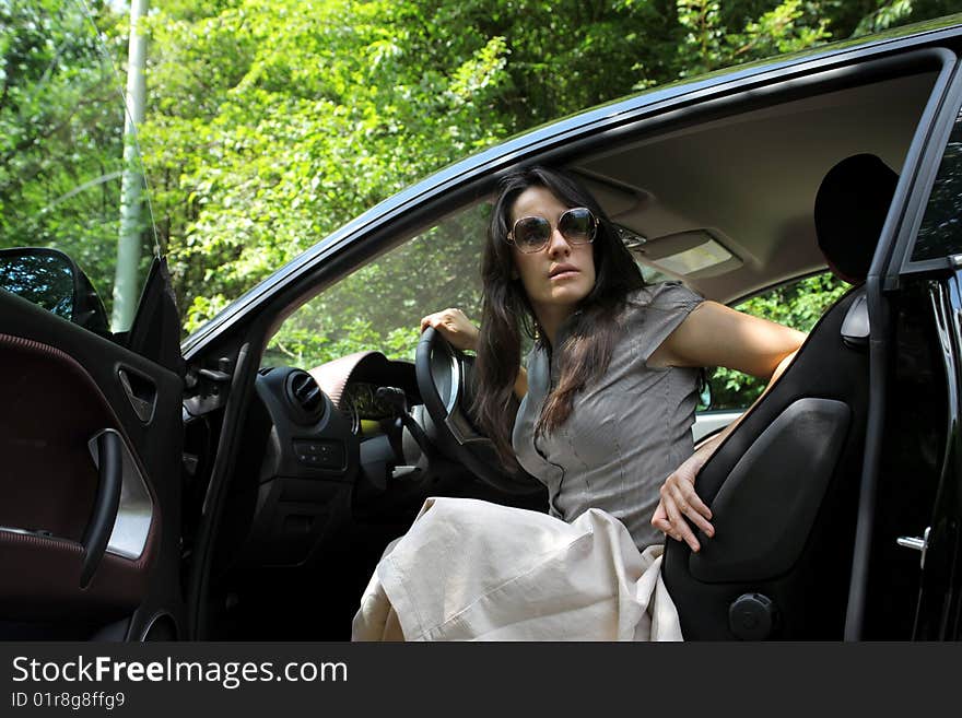 Beautiful girl seated in a car in a forest. Beautiful girl seated in a car in a forest