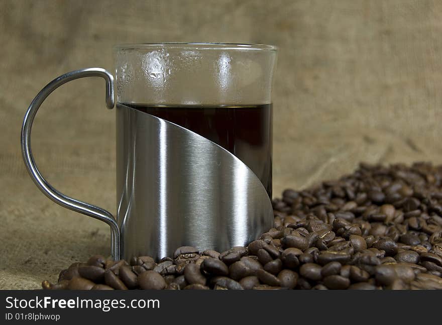 A cup of fresh coffee surrounded by coffee beans. A cup of fresh coffee surrounded by coffee beans