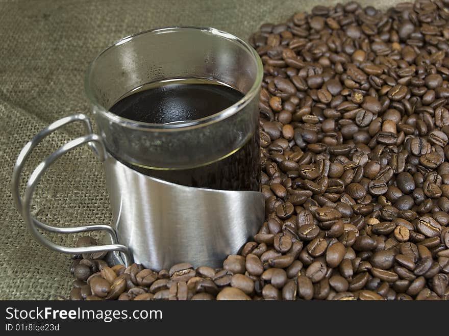 A cup of fresh coffee surrounded by coffee beans. A cup of fresh coffee surrounded by coffee beans