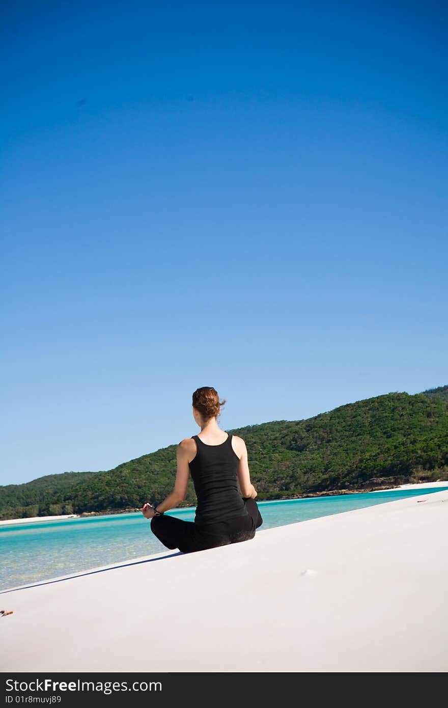 A young woman meditating on tropical beach near ocean waves. A young woman meditating on tropical beach near ocean waves