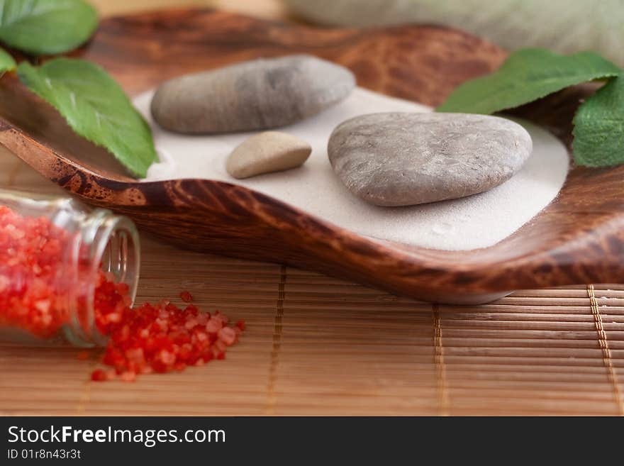 Massage stones on sand in a bowl and red bath salt. Massage stones on sand in a bowl and red bath salt