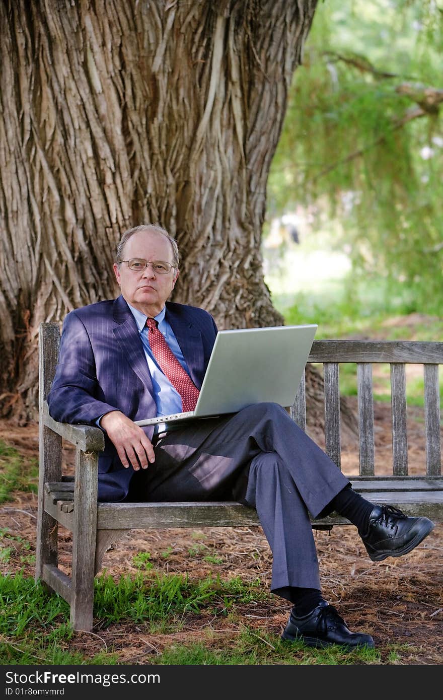 A business man looks into distance while using a laptop computer. A business man looks into distance while using a laptop computer