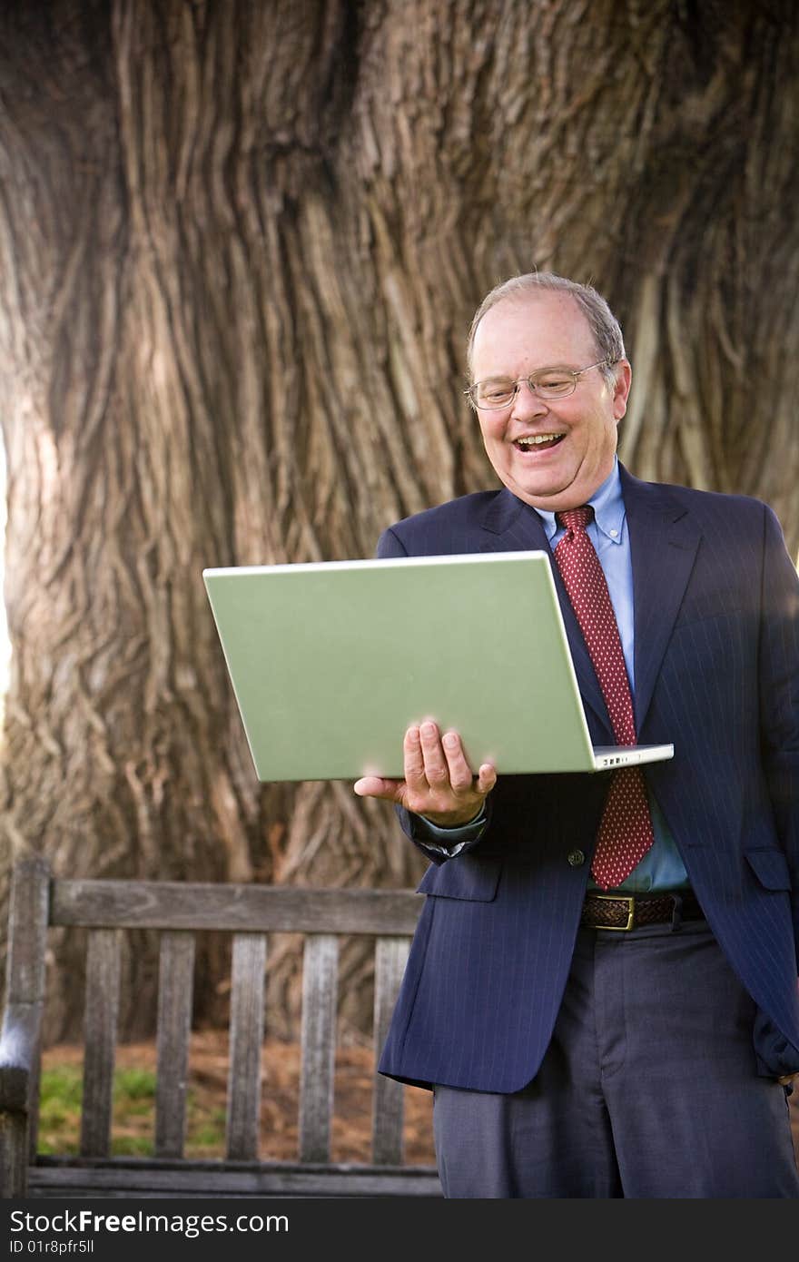 A business man laughs while working on his laptop computer. A business man laughs while working on his laptop computer