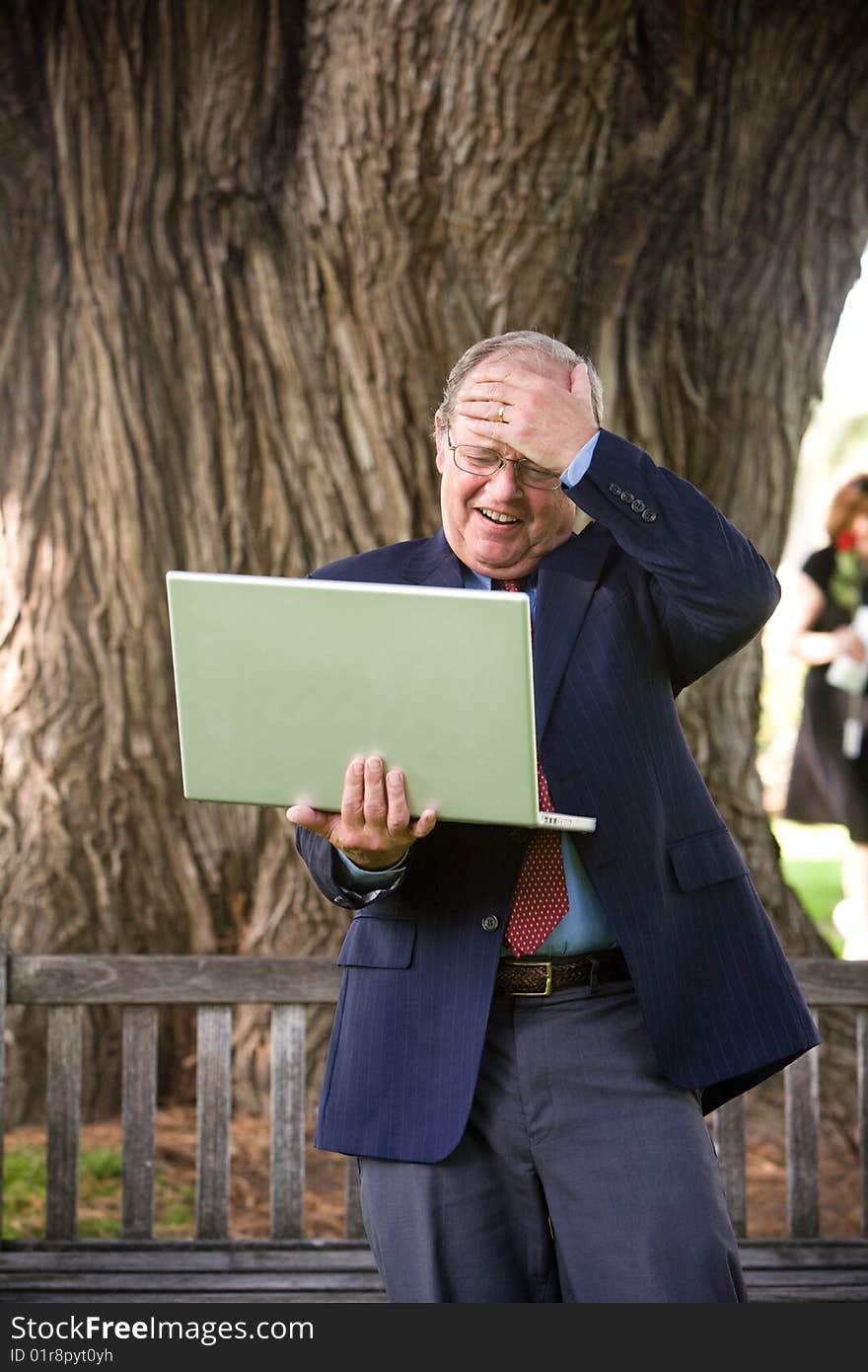 Surprised Man working on his laptop on park bench. Surprised Man working on his laptop on park bench