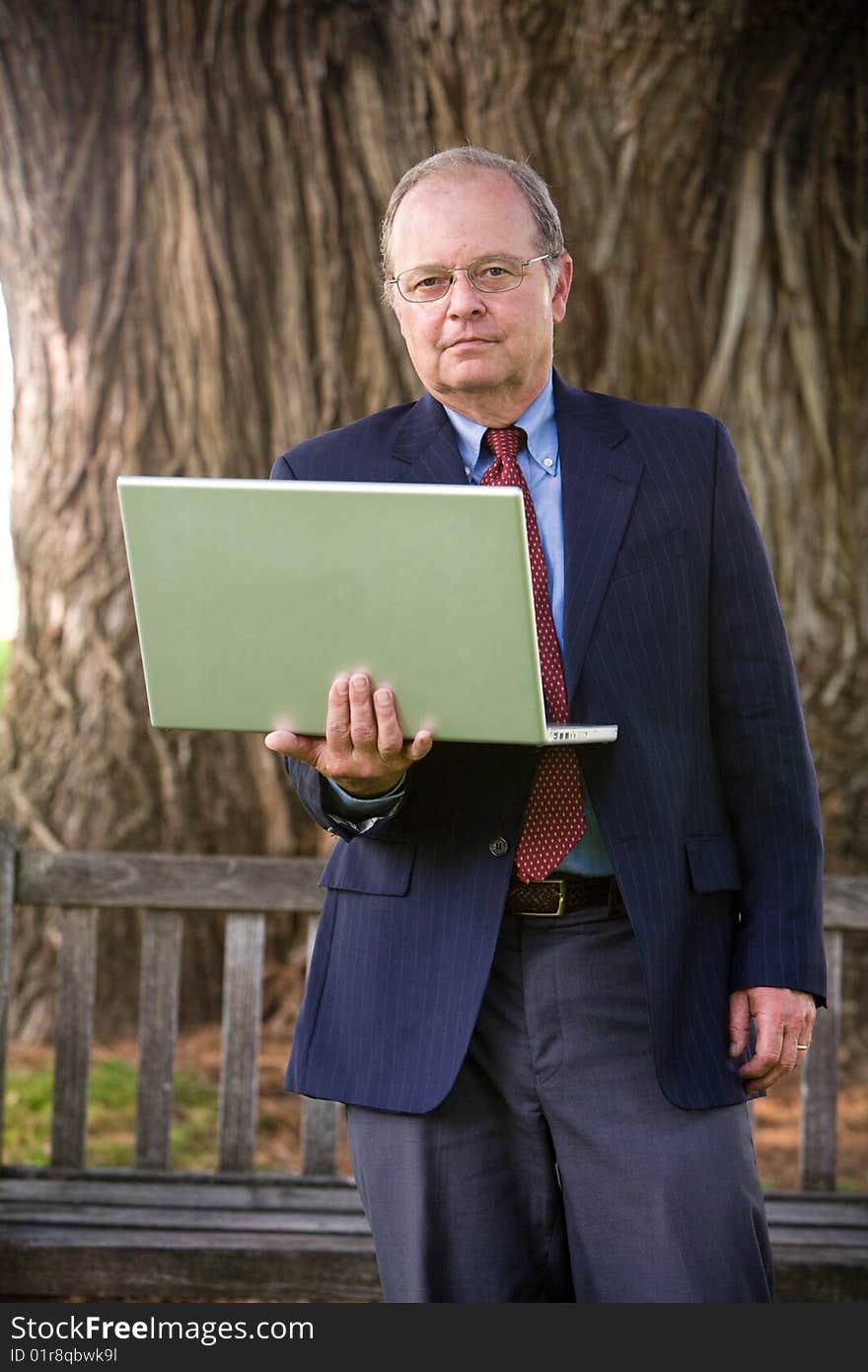 An man looks with his laptop computer on a park bench. An man looks with his laptop computer on a park bench