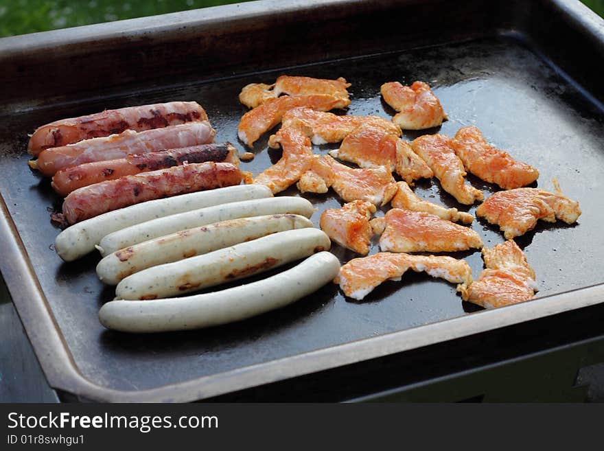 Meat and sausages on black grill. Meat and sausages on black grill