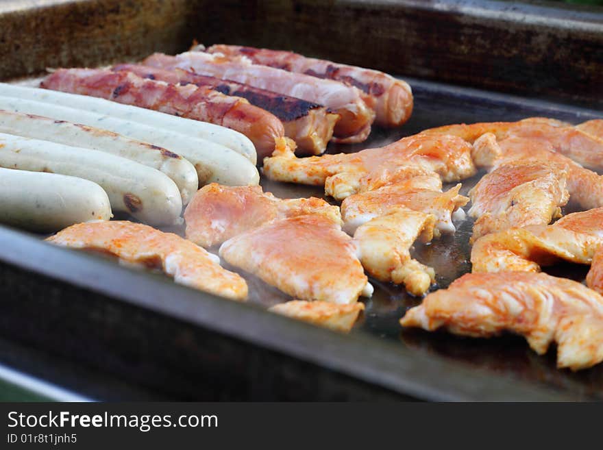 Meat and sausages on black grill. Meat and sausages on black grill