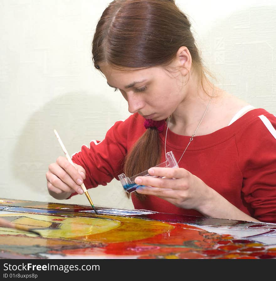 Young woman painting on the glass surface with vitrage dye. Young woman painting on the glass surface with vitrage dye