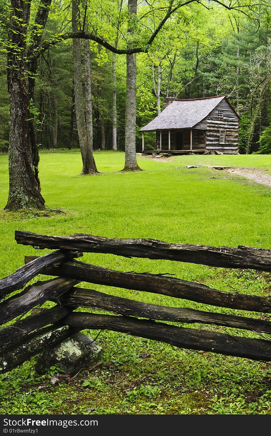 Cottege in forest with fence around it