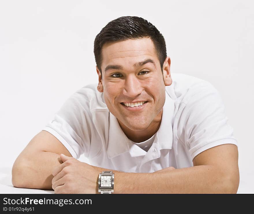 A young man is isolated in a white room.  He is wearing a white T-shirt and is smiling at the camera.  Horizontally framed shot. A young man is isolated in a white room.  He is wearing a white T-shirt and is smiling at the camera.  Horizontally framed shot.