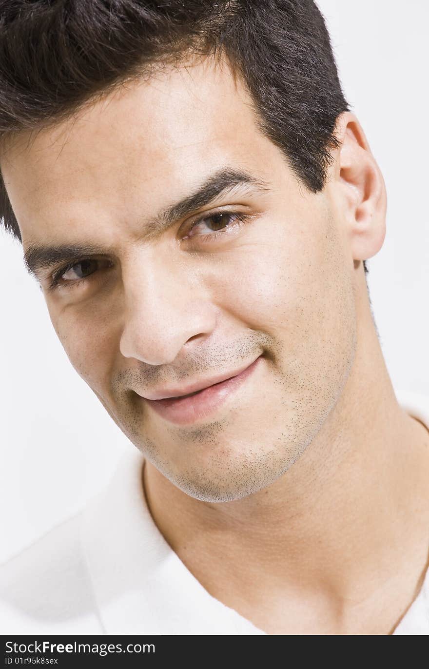 A close-up view of a man. He is smiling slightly and is peering into the camera. His head is tilted to the side. Vertically framed shot. A close-up view of a man. He is smiling slightly and is peering into the camera. His head is tilted to the side. Vertically framed shot.