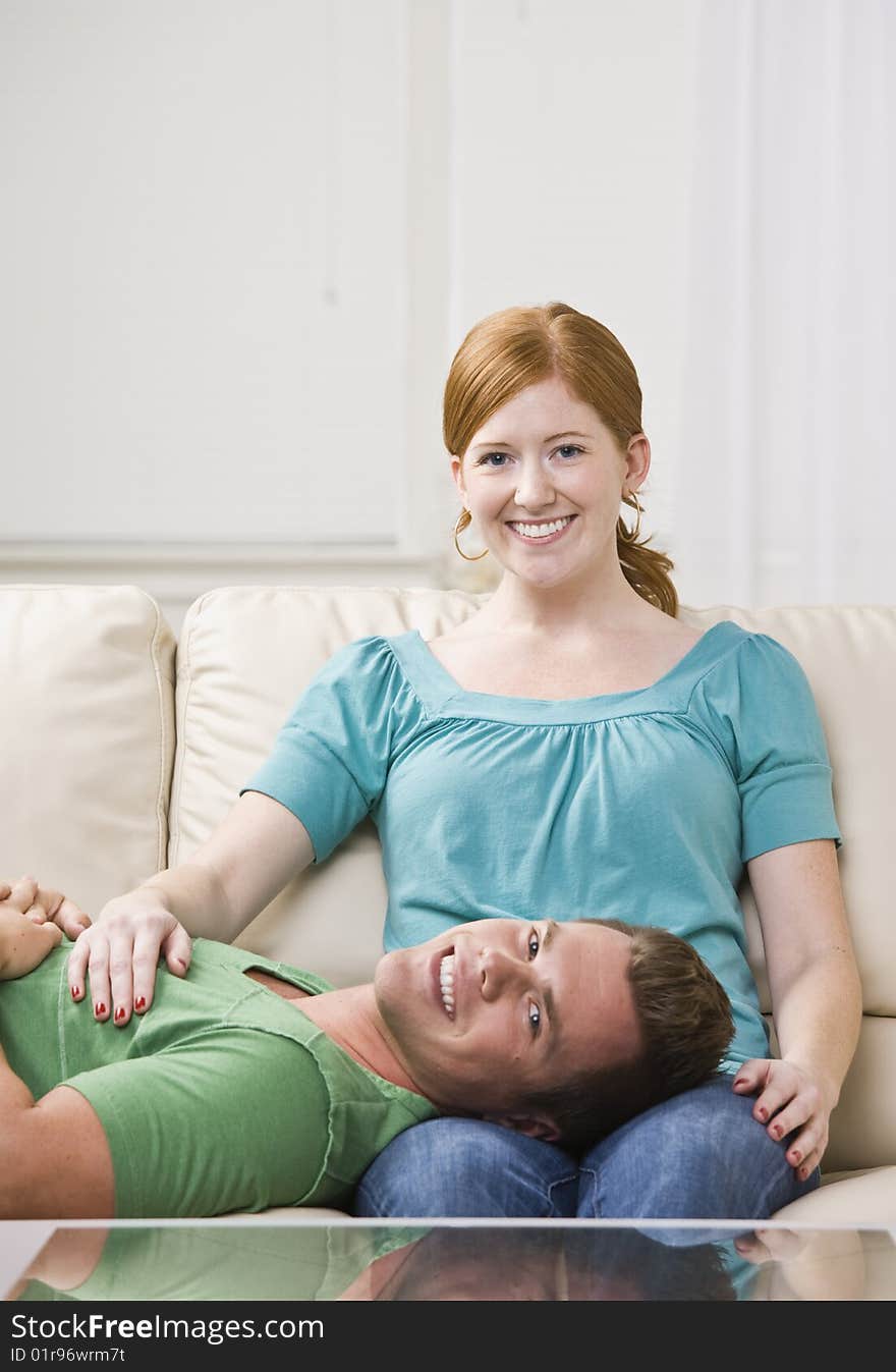 Attractive man lying down on a couch with his head in a woman's lap. Vertically framed photo. Attractive man lying down on a couch with his head in a woman's lap. Vertically framed photo.