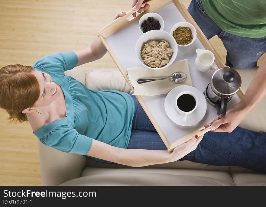 Woman being served breakfast on the couch.