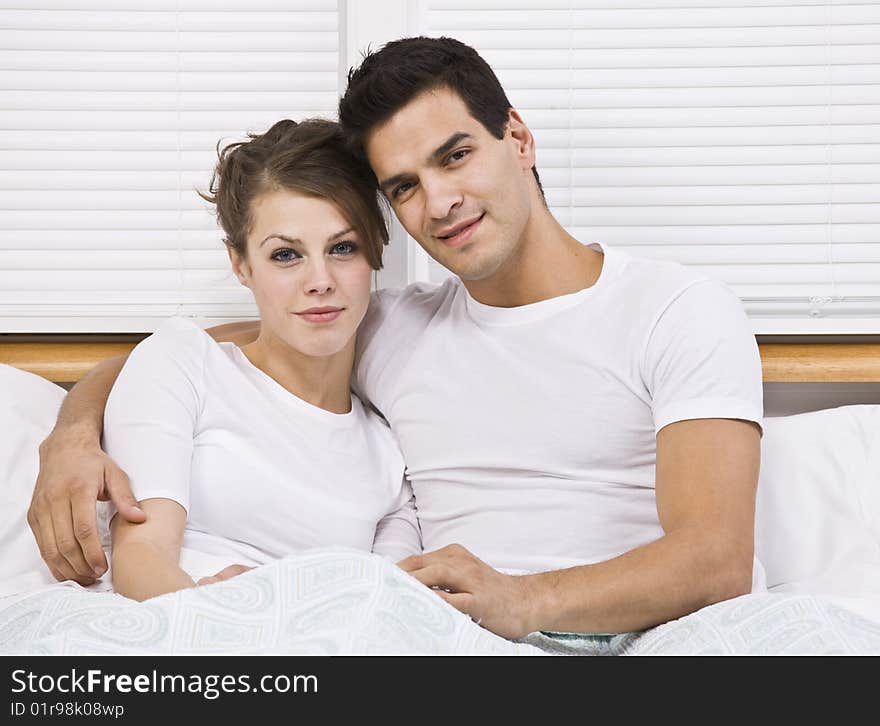 Male and female attractive couple snuggling in bed, horizontally framed. Male and female attractive couple snuggling in bed, horizontally framed